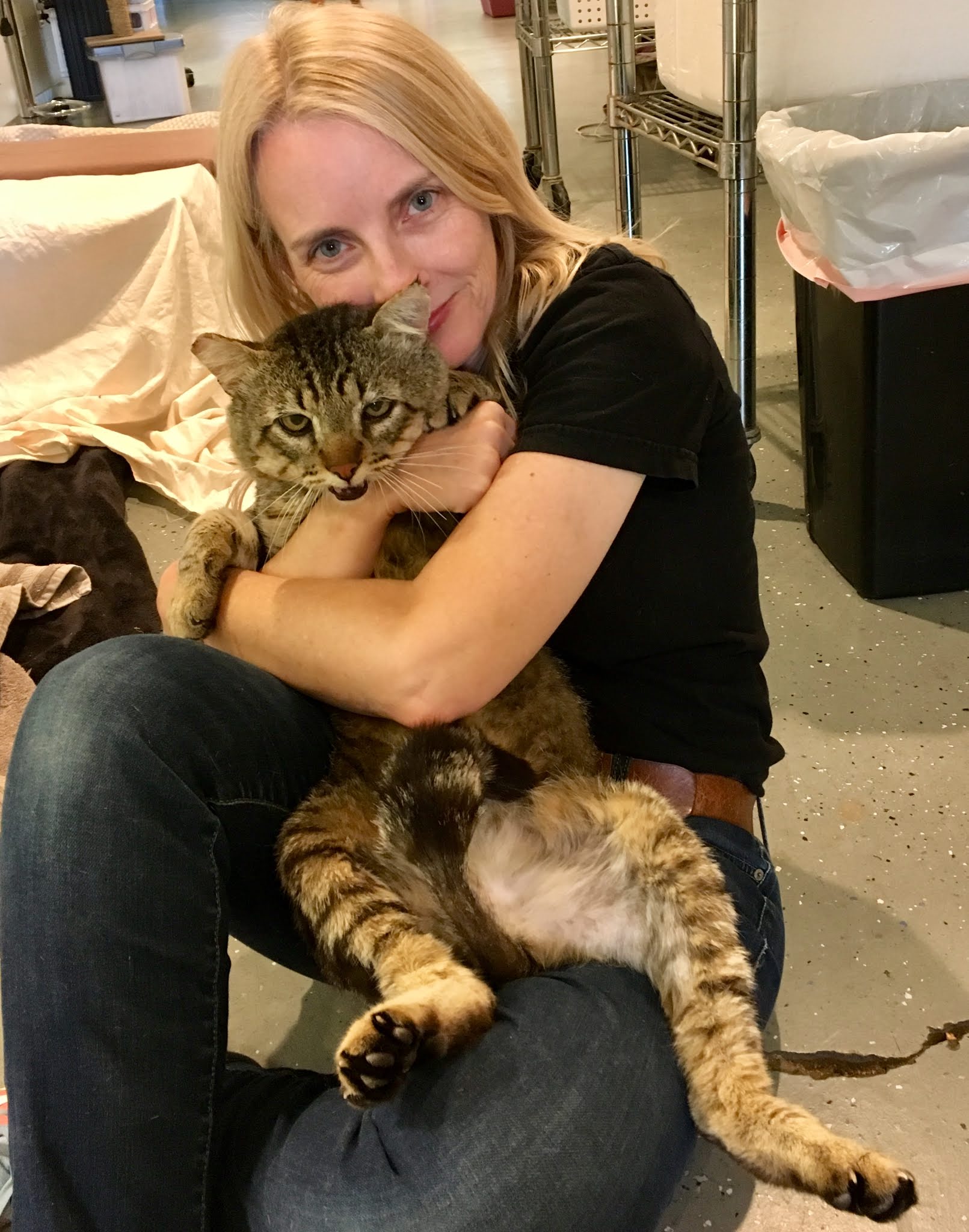 Bio photo of Dr Heather Kennedy, smiling, sitting and hugging a black and tan cat